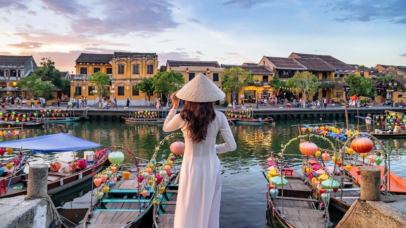 A woman in traditional Ao Dai dress overlooking the river in Hoi An